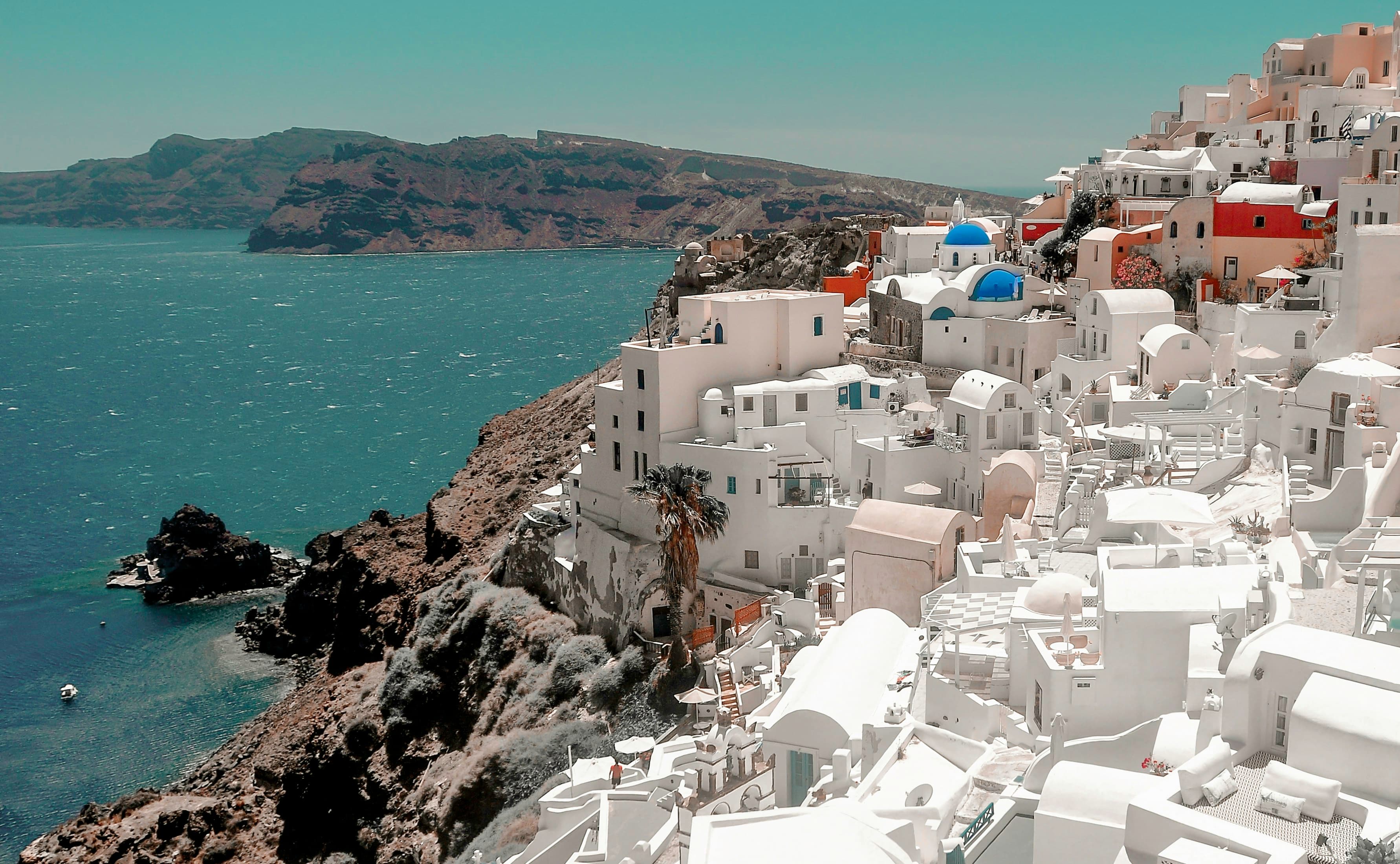 The iconic white-washed buildings and blue domes of Oia, Santorini, overlooking the Aegean Sea.